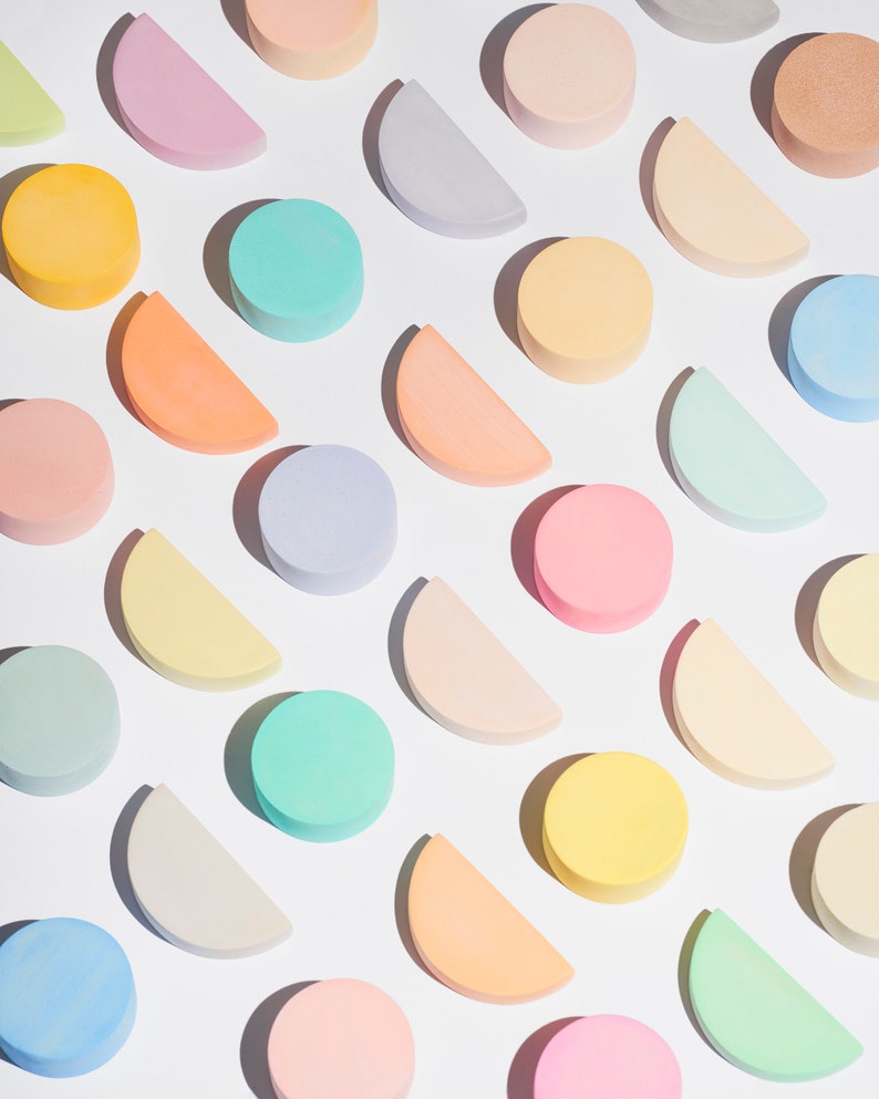 May include: A flat lay of pastel colored circles and half circles arranged in a diagonal pattern on a white background.
