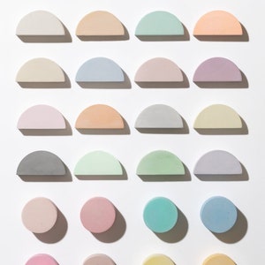Pode incluir: Uma vista a&eacute;rea apresenta uma cole&ccedil;&atilde;o de objetos decorativos coloridos, semicirculares e circulares. Os objetos est&atilde;o dispostos em um padr&atilde;o de grade, com uma variedade de tons pastel, incluindo rosa, azul, verde e amarelo. Os objetos s&atilde;o feitos de um material s&oacute;lido.