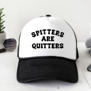 Puede incluir: Una gorra de camionero blanca y negra con el texto "Spitters Are Quitters" en letras retro negras.