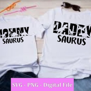 May include: Two white t-shirts with black dinosaur silhouettes and the text "Mommy Saurus" and "Daddy Saurus".