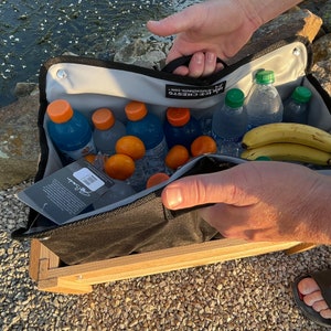 The inside insulated removable liner being removed from the coolers wooden frame with ice and drinks still inside the removable liner