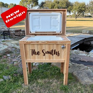 Pode incluir: Uma caixa de gelo de madeira com uma inscri&ccedil;&atilde;o personalizada que diz "The Smiths". A caixa de gelo tem um abridor de garrafas embutido e est&aacute; em um suporte de madeira. A caixa de gelo est&aacute; aberta e a tampa est&aacute; levantada.