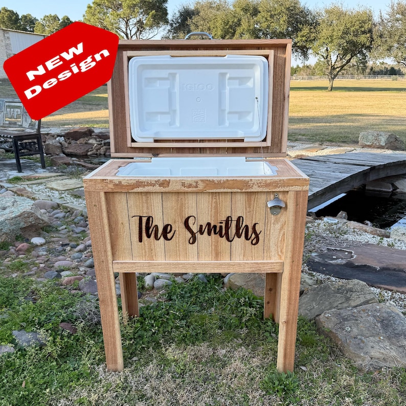 Pode incluir: Uma caixa de gelo de madeira com uma inscri&ccedil;&atilde;o personalizada que diz "The Smiths". A caixa de gelo tem um abridor de garrafas embutido e est&aacute; em um suporte de madeira. A caixa de gelo est&aacute; aberta e a tampa est&aacute; levantada.