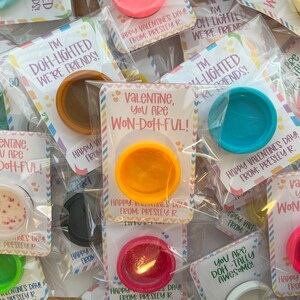 May include: A collection of Valentine's Day gifts featuring small containers of colorful playdough. Each container is packaged with a card that reads "Valentine, you are Won-Doh-Ful!" or "I'm Doh-lighted we're friends!"
