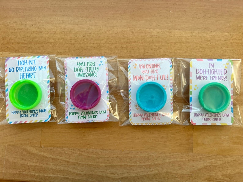 May include: Four Valentine's Day gifts in clear plastic packaging. Each card has a different message and a small container of colorful playdough. The messages include puns like "Doh-n't go breaking my heart."