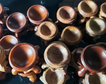 May include: A collection of wooden display stands with three legs and a round top. The stands are made of dark brown wood and are perfect for displaying small objects.