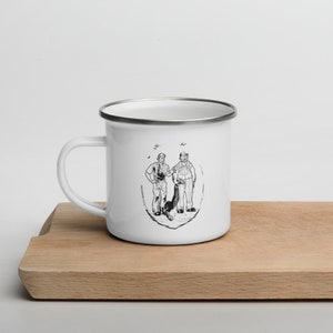 May include: White enamel mug with a black and white illustration of two people and a dog. The illustration shows two people standing side-by-side, one holding a leash attached to a dog.
