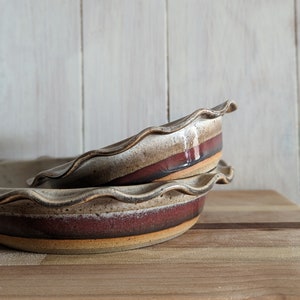 Stoneware pie dish with smokey black and grey glaze layered with emerald green/red glaze on bottom