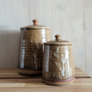 Stoneware jar with pumpkin orange, smokey glaze and white painted stem on one side