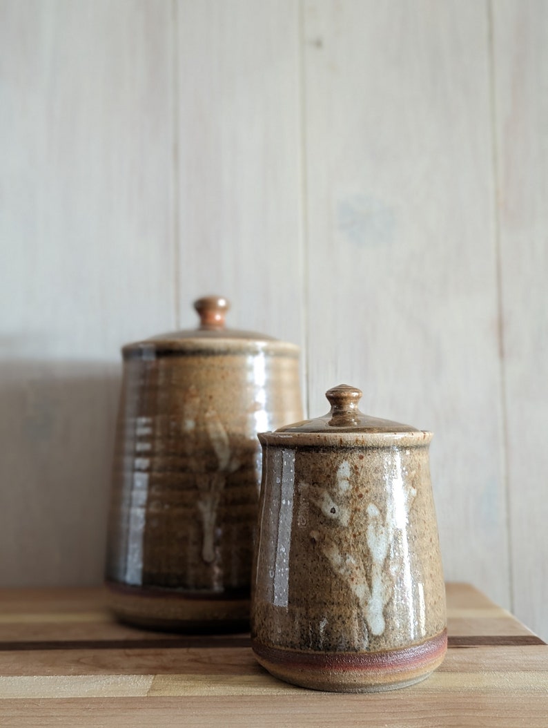 Stoneware jar with pumpkin orange, smokey glaze and white painted stem on one side