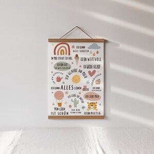 May include: A colorful poster with a rainbow, a sun, a house, a cactus, a tiger, and a hot air balloon. The poster has text in German that says "Ich kann alles schaffen" (I can do everything) and "Ich bin mutig" (I am brave).