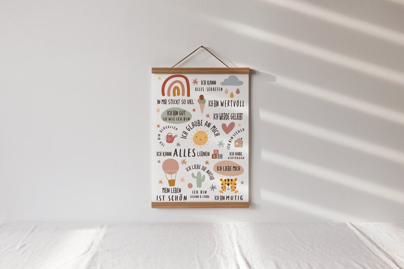 May include: A colorful poster with a rainbow, a sun, a house, a cactus, a tiger, and a hot air balloon. The poster has text in German that says "Ich kann alles schaffen" (I can do everything) and "Ich bin mutig" (I am brave).