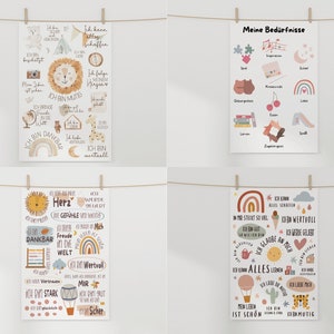 May include: Four colorful posters with illustrations and text in German. The posters are hung on a white wall with clothesline and clothespins. The posters feature illustrations of animals, hearts, rainbows, and other objects. The text on the posters includes phrases like "Ich bin dankbar" and "Ich bin mutig".