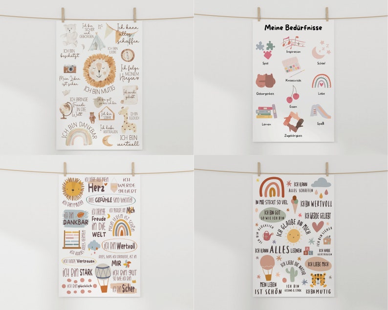 May include: Four colorful posters with illustrations and text in German. The posters are hung on a white wall with clothesline and clothespins. The posters feature illustrations of animals, hearts, rainbows, and other objects. The text on the posters includes phrases like "Ich bin dankbar" and "Ich bin mutig".
