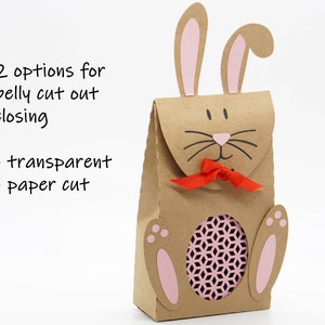 Puede incluir: Una bolsa de regalo de papel marr&oacute;n en forma de conejo con orejas y patas rosas. La bolsa tiene un vientre recortado con un inserto de papel rosa estampado. La bolsa tiene una cinta roja atada alrededor del cuello. El texto "2 opciones para el cierre del vientre recortado - transparente - corte de papel" es visible en la imagen.