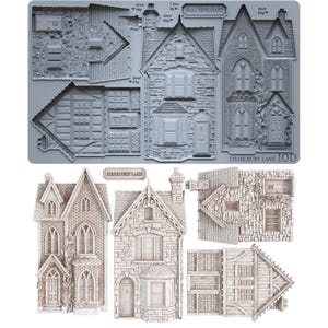 May include: A gray silicone mold sheet labeled Charlbury Lane featuring recessed cavities for casting architectural house elements, including walls, roofs, and windows, with volume measurements in ml and weight in grams printed near each section.