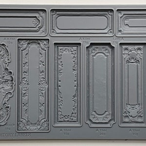 May include: Gray silicone mold featuring various ornate label designs, including rectangular and oval frames with floral and scrollwork details. The text "IOD CONSERVATORY LABELS" is visible. Measurements are indicated in milliliters and grams.