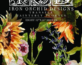 Op de afbeelding: Iron Orchid Designs Painterly Florals transfer-set met acht vellen van 30,5 cm x 40,6 cm. De zwarte verpakking toont het merklogo, de tekst en een levendige illustratie van gele zonnebloemen, roze rozen en blauwe wilde bloemen in schilderstijl.