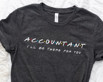 Puede incluir: Una camiseta gris oscuro con el texto "ACCOUNTANT I'LL BE THERE FOR YOU" en blanco con puntos de colores. El texto está estilizado para parecerse al logotipo de la serie Friends.