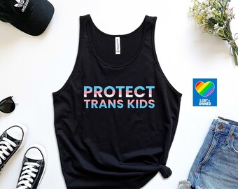 May include: Black tank top with the text "PROTECT TRANS KIDS" in rainbow colors. The text is layered with a transgender pride flag design. A small sticker with a rainbow heart and the text "LGBT+ OWNED" is also visible.