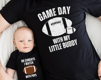 Puede incluir: Una camiseta negra con el texto "Game Day with my Little Buddy" y un gráfico de fútbol. Un body de bebé negro con el texto "On Sundays I Watch with Pops" y un gráfico de fútbol.