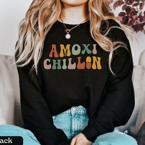 May include: A black sweatshirt with the text "AMOX! CHILLIN" in colorful retro font.