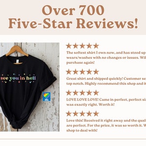 Puede incluir: Camiseta negra con el texto "see you in hell" en colores arco&iacute;ris. La camiseta est&aacute; en una percha y tiene un logotipo de coraz&oacute;n arco&iacute;ris en la esquina inferior derecha. La imagen est&aacute; acompa&ntilde;ada de rese&ntilde;as de cinco estrellas de los clientes.