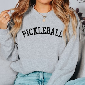May include: A gray sweatshirt with the word "PICKLEBALL" printed in black on the front.