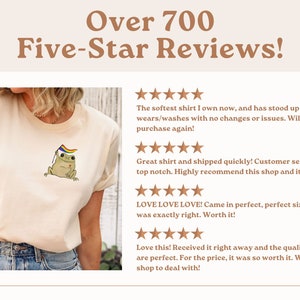 May include: A close-up of a white t-shirt with a frog wearing a rainbow flag on its head. The shirt has over 700 five-star reviews. The reviews highlight the soft fabric, quick shipping, and excellent customer service.