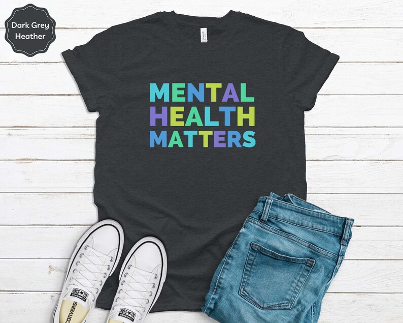 Puede incluir: Camiseta de color gris oscuro jaspeado con el texto "MENTAL HEALTH MATTERS" en colores arco&iacute;ris.