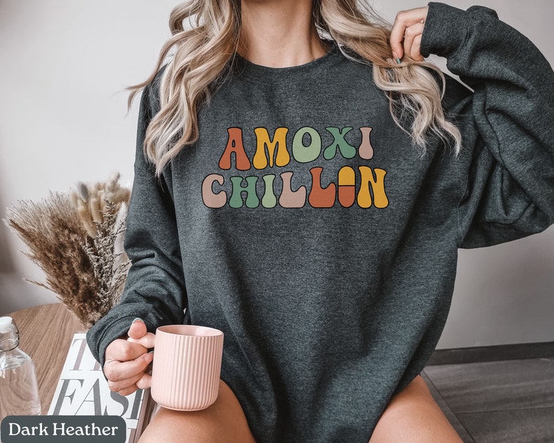 May include: A dark heather grey sweatshirt with the text "MOXI CHILLIN" in colorful retro-style lettering.