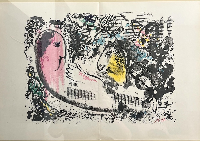 May include: Abstract art print featuring a pink face, a yellow horse head, and a figure in green. The artwork uses black, blue, and pink brushstrokes, with a signature in the lower right corner. The print is on white paper.