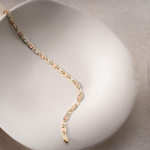 Puede incluir: Una pulsera de cadena de oro tricolor con eslabones ovalados y rectangulares texturizados que se alternan en tonos de oro amarillo, rosa y blanco. La pulsera tiene un acabado pulido con detalles grabados en los segmentos rectangulares.