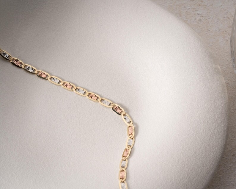 Puede incluir: Un collar de cadena de oro tricolor con eslabones ovalados alternos en oro amarillo, rosa y blanco. Cada eslab&oacute;n presenta un grabado texturizado estilo rayos de sol en su superficie, creando un patr&oacute;n repetitivo de tonos met&aacute;licos.