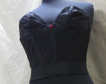 May include: Black satin corset with a lace trim and a red button detail.