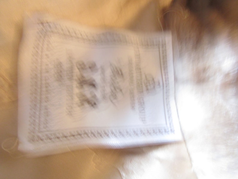May include: A white fur coat with a white label that says "Furrier to the Stars" and "Made in Italy".