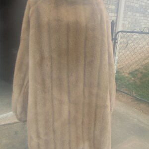 May include: A long, brown fur coat with a high collar. The coat is made of a soft, luxurious fur and has a classic, elegant style.