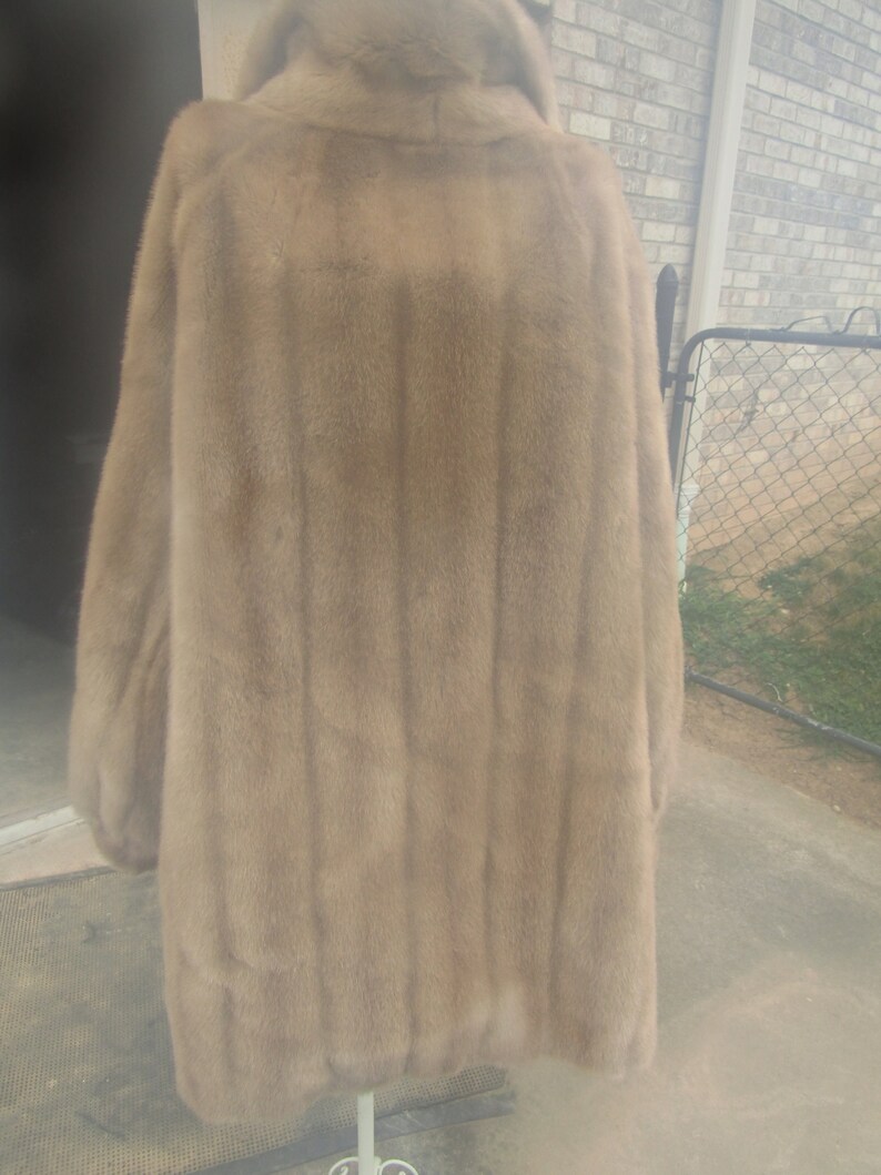 May include: A long, brown fur coat with a high collar. The coat is made of a soft, luxurious fur and has a classic, elegant style.