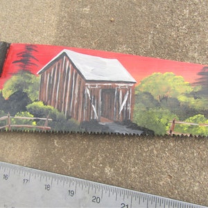 hand painted barn on saw blade with red back ground