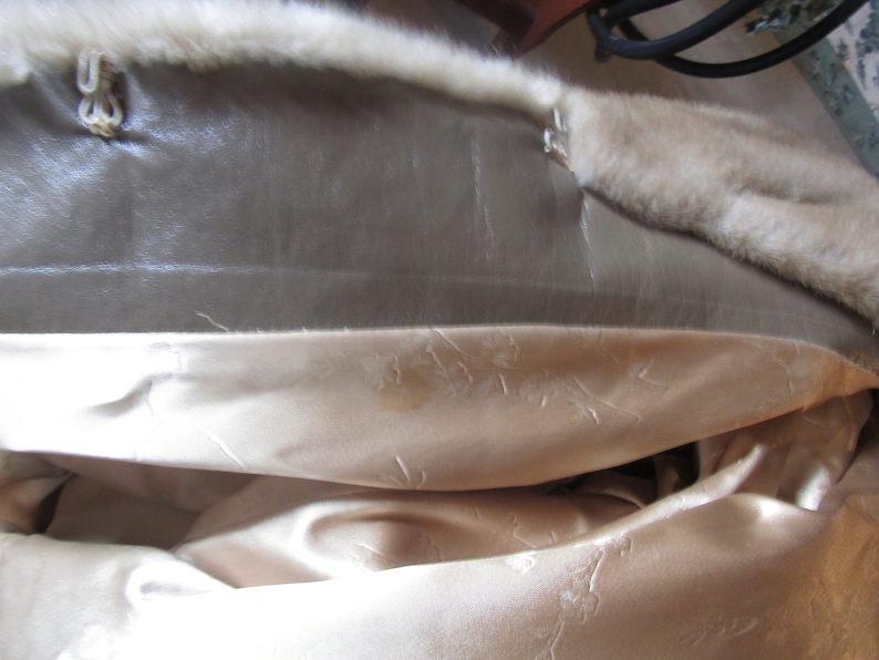 May include: The inside of a fur coat with a brown leather lining and a white satin lining.