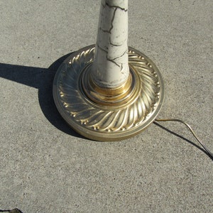 May include: A white floor lamp with a gold base and a marbled design. The lamp has a cord and plug.