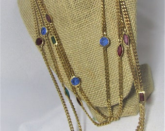 May include: A gold chain necklace with multiple strands and colorful gemstones. The necklace features blue, red, and green stones.