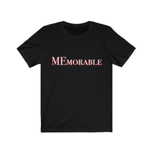 Puede incluir: Camiseta negra de manga corta con la palabra "MEMORABLE" impresa en blanco con un contorno rojo.