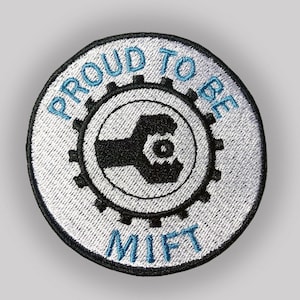 May include: A white and blue embroidered patch with the text "Proud to be MIFT" and a black gear with a hand holding a wrench inside.