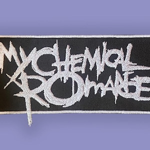 Może przedstawiać: Czarna prostokątna naszywka z białym haftowanym napisem „My Chemical Romance”. Tekst jest w stylizowanej, postarzonej czcionce. Naszywka ma białą obwódkę i znajduje się na liliowym tle.