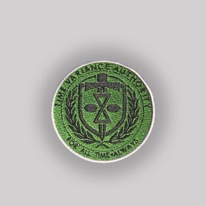May include: A circular green patch with the text "TIME VARIANCE AUTHORITY" around the edge. The center features a black emblem with a cross, hourglass, and other symbols. The words "FOR ALL TIME ALWAYS" are at the bottom.