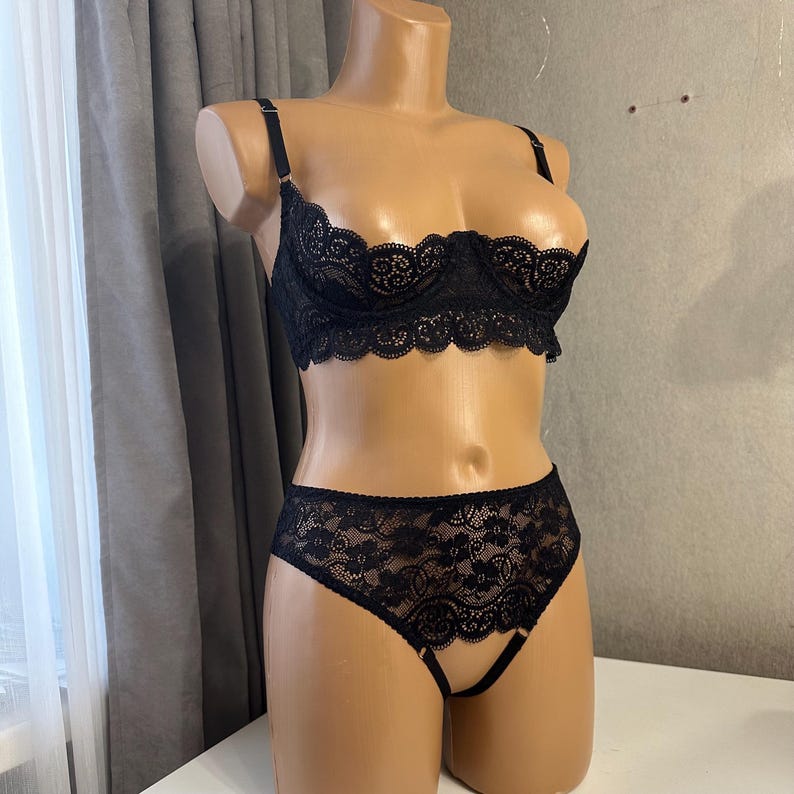 May include: Black lace lingerie set featuring a bra and panty. The bra has a plunging neckline and the panty has a cutout detail.