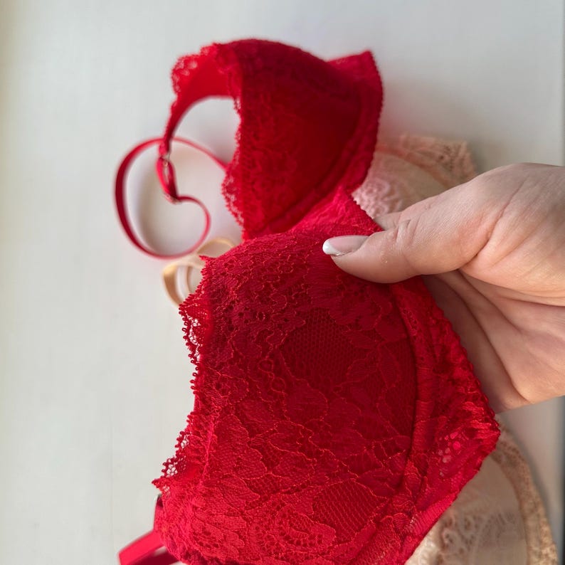 May include: A red lace bra with delicate floral patterns. The bra is made of soft, sheer fabric and has adjustable straps.