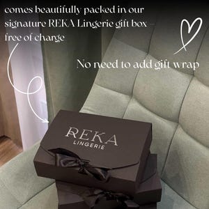 May include: Three dark brown gift boxes with black satin bows are stacked on a light green chair. The top box has the text "REKA LINGERIE" in silver. Text in the image states "Each order comes beautifully packed in our signature REKA Lingerie gift box free of charge. No need to add gift wrap."