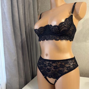 May include: Black lace lingerie set featuring a bra and panty. The bra has a plunging neckline and the panty has a cutout detail.